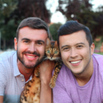 Two smiling men holding a cat
