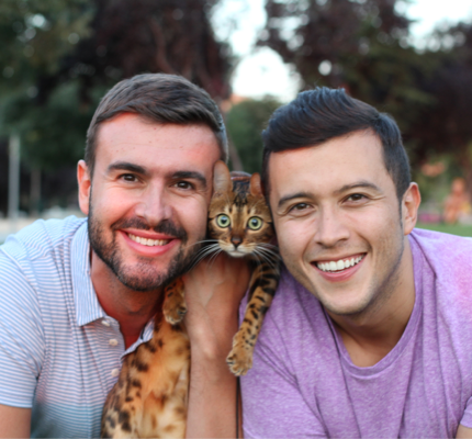 Two smiling men holding a cat